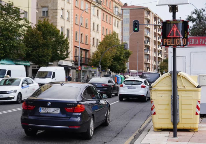  Rue animée à Salamanca avec des voitures en circulation, un feu de signalisation vert et un panneau d'avertissement de vitesse indiquant 'PELIGRO'.