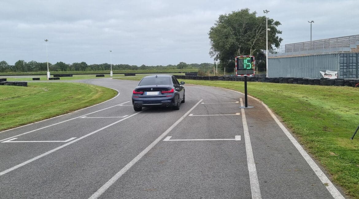 A car drives on a go-kart track while the EVOLIS radar speed sign measures its speed.